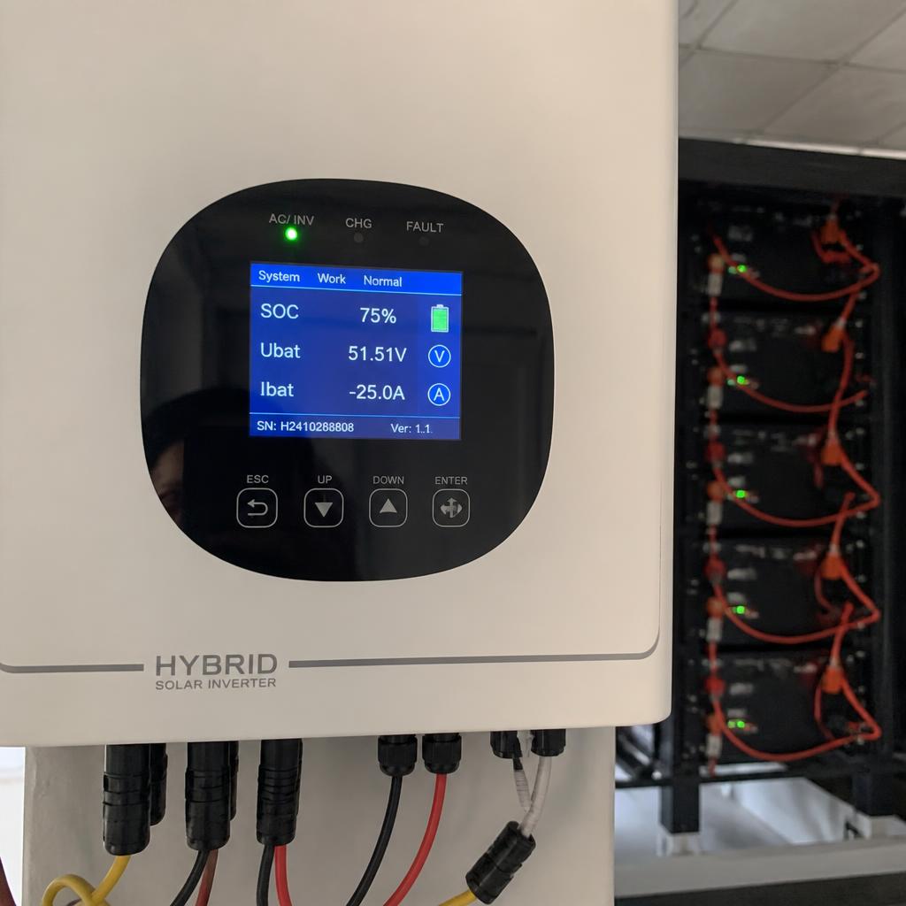 Màn hình inverter hybrid hiển thị thông số SOC pin, điện áp battery, dòng sạc/xả sau khi lắp đặt xong, chụp thực tế tại công trình, có thể thấy pack pin phía sau